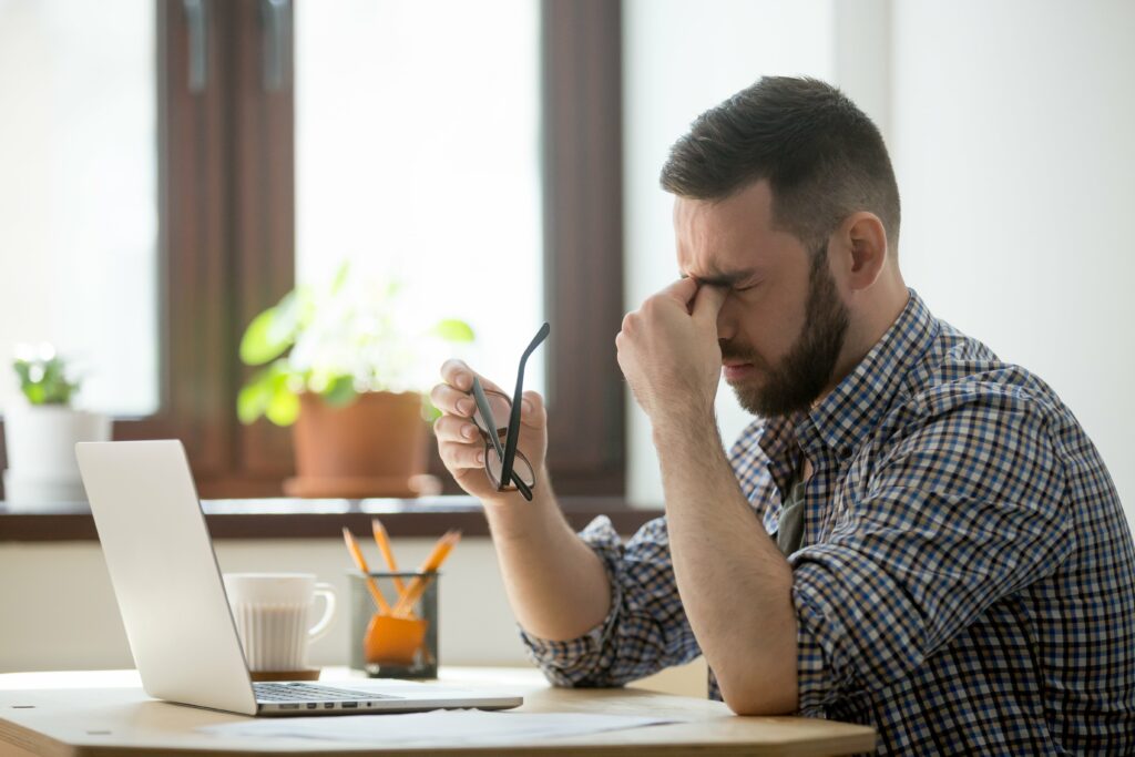 Homme pensif et stressé devant son ordinateur en télétravail